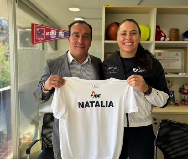 Natalia Duco, embajadora de los Juegos Deportivos Escolares, posa sonriente junto al Director Nacional del IND, Israel Castro, con una camiseta con el logo de los Juegos Deportivos Escolares y su nombre, Natalia.